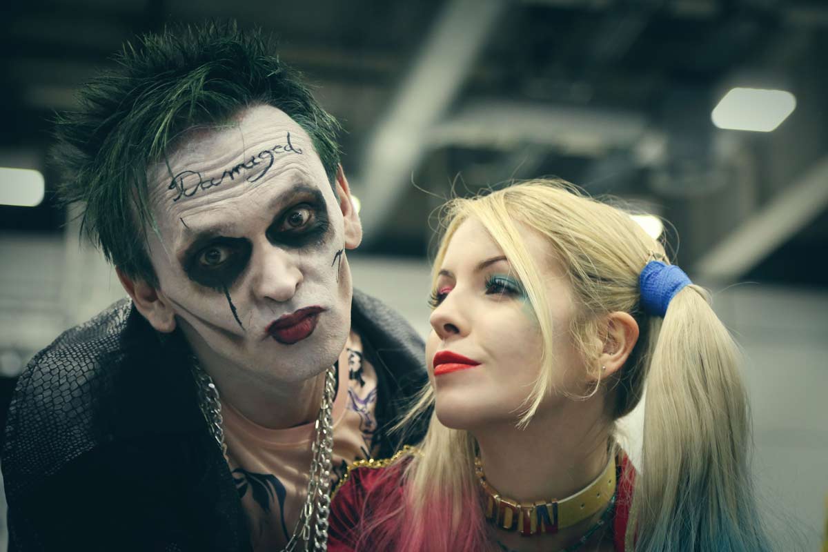 Δύο μεταμφιεσμένοι ως Joker και Harley Quinn ποζάρουν με εντυπωσιακό μακιγιάζ σε εκδήλωση cosplay.